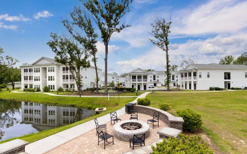 a large white building with a pool and a lawn with a table and chairs