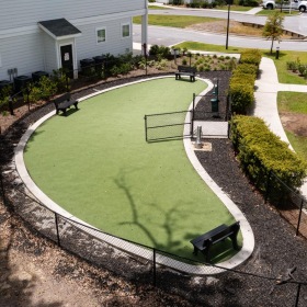 a large green courtyard with a building and a car parked in it